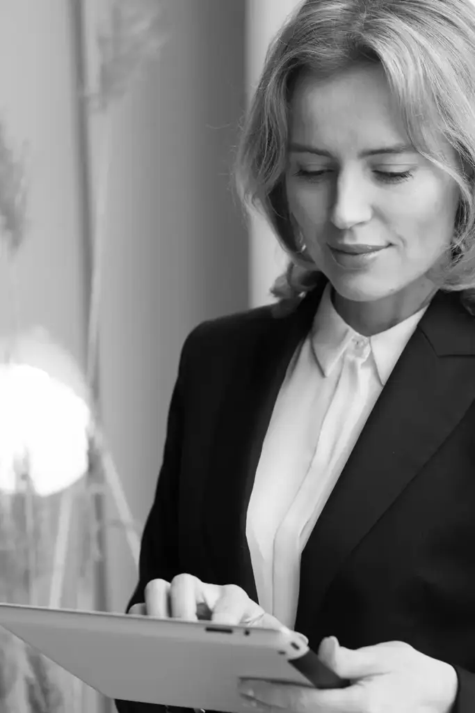 Modern bir ofis ortamında tablet kullanan profesyonel bir iş kadınının şık siyah beyaz portresi.